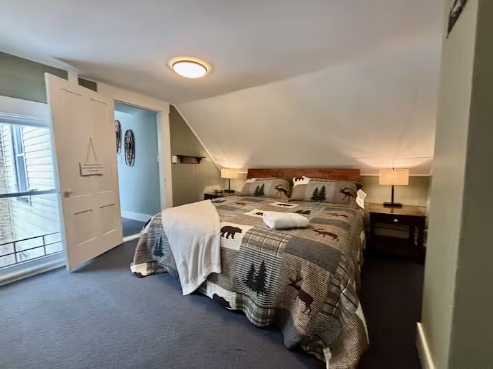 Bedroom at 56 Main Street with a rustic quilt under a slanted ceiling