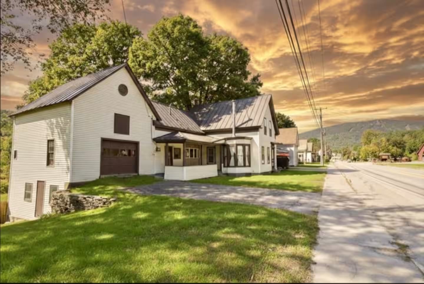 Exterior of 56 Main Street, a white clapboard home in Ludlow, Vermont at golden hour
